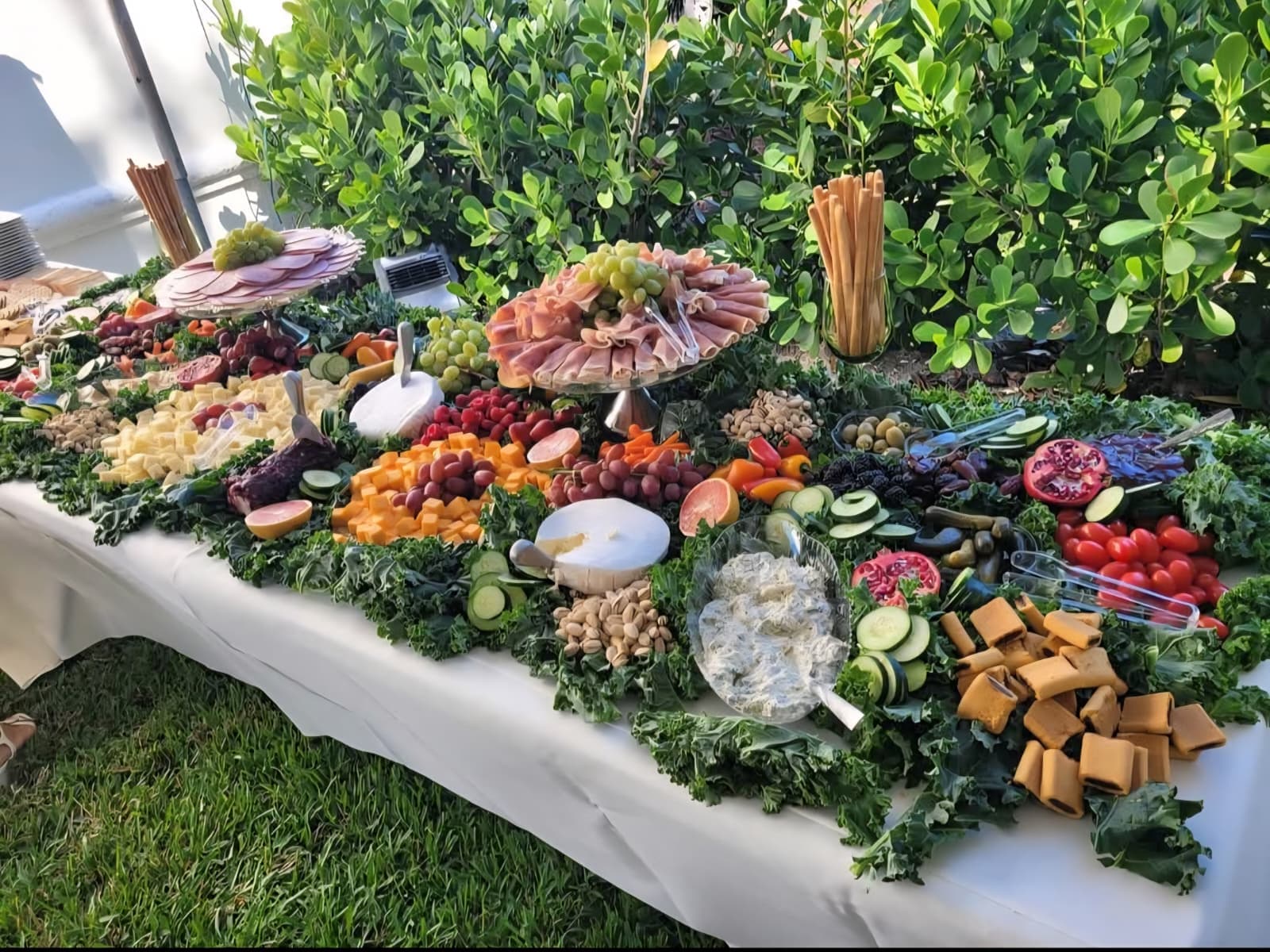 Outdoor grazing table with charcuterie, cheeses, and fresh produce